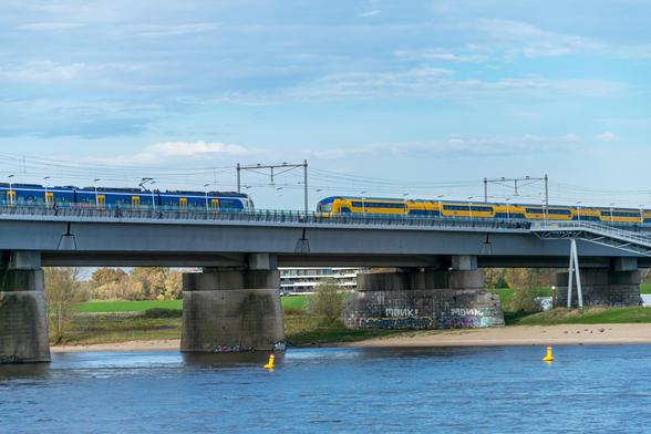 Yellow-blue double decker train and a blue-white-yellow regional train on a bridge