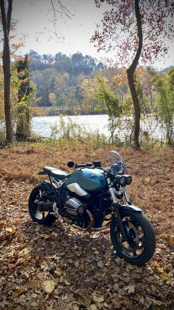 The aquamarine BMW motorcycle on the banks of the river.  If you zoom in above the river you can see a flock of geese squawking in the background