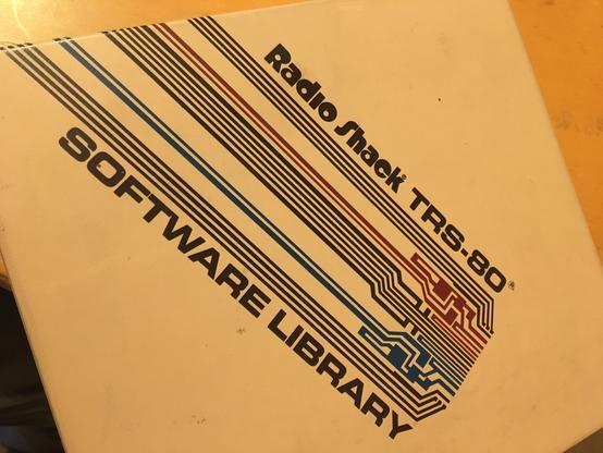 Cover of Radio Shack TRS-80 Software library binder, with a dramatic geometric design which could represent both pcb traces as well as layer masks on integrated circuits. The text is rendered in the TRS-80 brand Eurostile typeface.