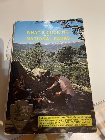 A well worn book of recipes on a beige counter
WHAT'S COOKING
NATIONAL PARKS
NATIONAL
PARK
SERVICE
Department
of the interior
A choice collection of over 500 highly prized recipes
from employees of our National Parks. Includes a
unique section on OUTDOOR COOKING and over
30 photos from our vast National Park System.
$3.80