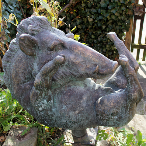 Bronzeskulptur eines auf dem Rücken liegenden Wildschweins.