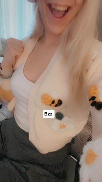 Ada wearing a yellow cardigan with bees and white flowers embroidered on it