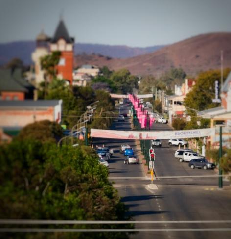 Looking eastward down a bedecked street. A clock tower to the north and a round hill in the distant