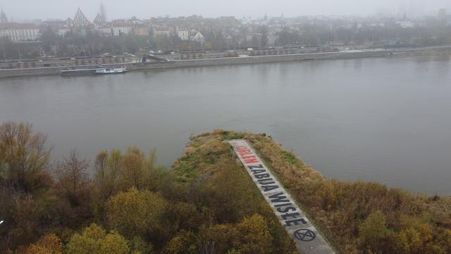 Widok z lotu ptaka na Wisłę i Stare Miasto w Warszawie. Na pierwszym planie ostroga z wymalowanym na betonie olbrzymim napisem "Orlen zabija Wisłę".