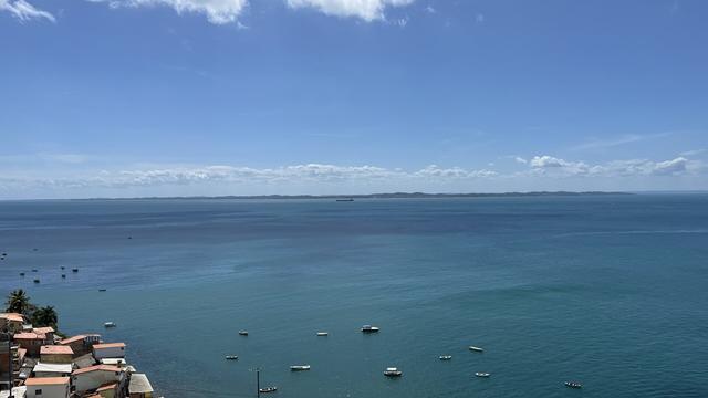 Un océano de mar transparente, mirado desde arriba, donde se ven a lo lejos algunas lanchas o yatchs