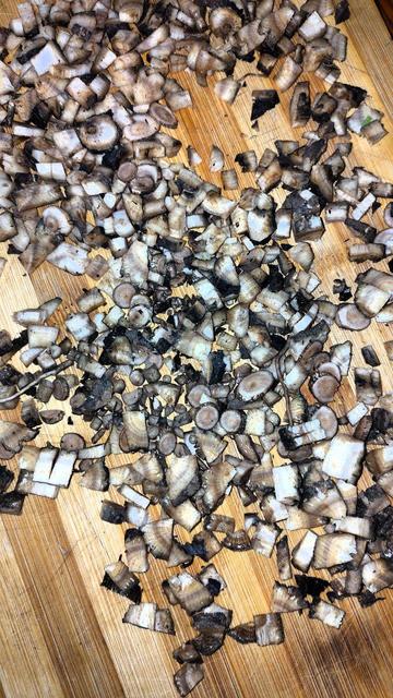 Arrel de bardana trossejada, sobre una fusta de tallar