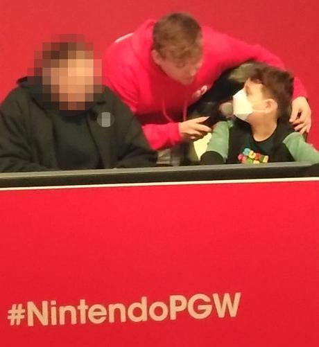 Sur le podium du stand Nintendo de Paris Games Week 2025,  un héro masqué (FFP2) est interviewé par un  journaliste.