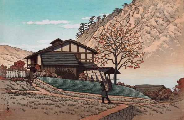 A bright autumn day on a farm in Gunma, Japan. A figure carrying a woven basket of what might be kindling trudges up a narrow path toward a farmhouse. Just in front of the house, a wide, tidy vegetable patch is full of green plants; nearby, a tall persimmon tree has already shed its leaves, and only the season's fruit remains clinging to the branches. Foliage on the ground and the surrounding mountains has rusted red-brown; above, a few puffy white clouds cross a bright blue sky.