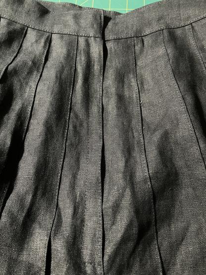 The side zipper is almost invisible on the black pleated skirt with edge stitching details