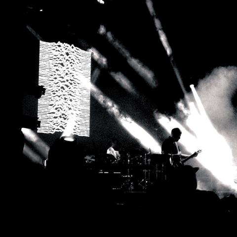 Silhouette of a guitarist against a light projection of wavy lines