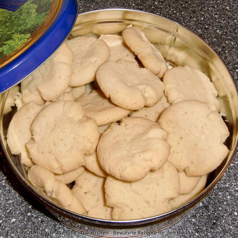 Auf der Küchenplatte steht eine Blechdose randvoll mit hellgelben Schmalzplätzchen. Die Ränder sind unregelmäßig dekorativ eingerissen durch das Plattdrücken vor dem Backen.