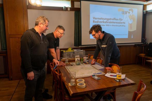 Drei Männer begutachten eine Karte der Gemeinde Sitzenberg-Reidling beim ersten Treffen für Radverkehrsinteressierte am 18.10.2025 im Gasthaus Dopler.