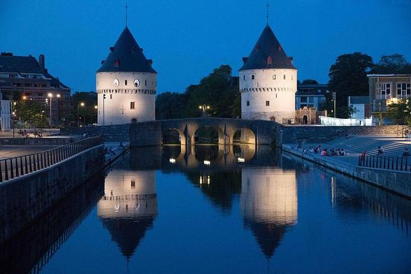 two towers with a bridge and water in between them. Mideavel towers, white bricks.
The tower on the left has eyes attached to it .. as a gimmick or art project.
Pic taken at evening time.