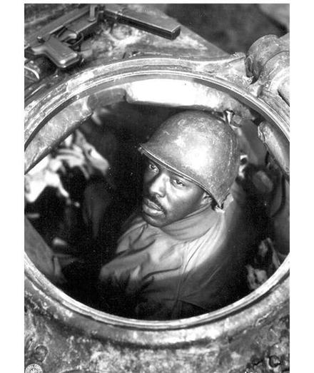 A Black soldier from the 761 Tank Battalion looks up from his tank.