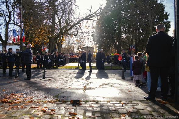 Les autorités publiques entrent sur la place de la République, pour un salut au drapeau et une revue des troupes, pendant que l’Harmonie joue « la Marseillaise » et que des enfants sont sur le côté.