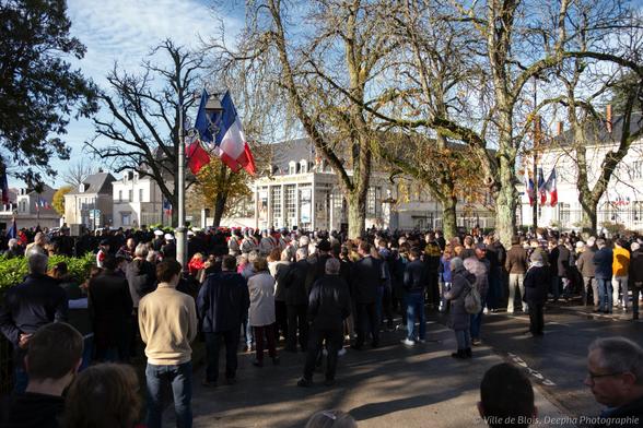 La foule est rassemblée sous les arbres de la place de la République, pendant la cérémonie.