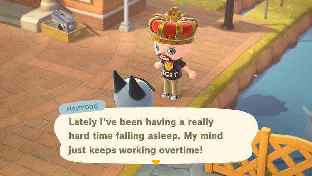 Animal Crossing: New Horizons screenshot. Image set in the brick town center. Raymond (grey cat with black ears) is partially visible sitting on the ground from behind. He is talking to a light skinned, bearded, bald human wearing an oversized golden / red crown and a black t-shirt with Redd's face on it. A large speech box below indicates Raymond is talking.  He is saying, "Lately I've been having a really hard time falling asleep. My mind just keeps working overtime!"
