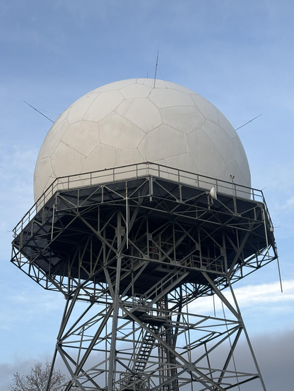 A white spherical object (an antenna of some sort?) atop a trestle platform.

The surface of the sphere is divided into pentagonal and hexagonal panels, but not in the usual way.  Each hexagon has two consecutive angles of _almost_ 90°, which then match up to a corresponding angle of _almost_ 180° on another hexagon.  The other three angles are close to 120°.

The visible pentagons appear to be regular.