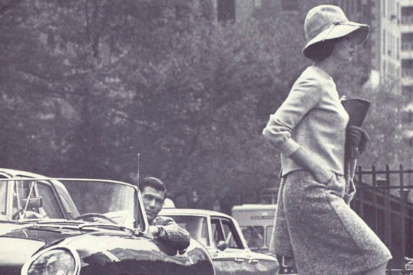 1964 Vintage Fashion in Urban Setting

In this black and white photograph, a woman dressed elegantly with wide-brimmed hat is captured walking through an urban landscape. She carries what appears to be a cup or small container in her right hand. Her attire suggests fashion from the mid-20th century.

To her left, there's a man inside a convertible car gazing outward, seemingly engaged by something outside of his vehicle. His casual pose and streetwear contrast with the woman's formal appearance.

The background is populated with parked cars, indicative of an urban environment at that time period. The focus on fashion during this era hints at possible themes related to historical style trends or societal roles in mid-20th-century cities.

None
