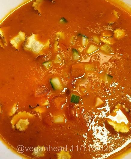 A bowl of Carrot & Ginger Soup, topped w/ fresh cucumber & tomato. Served w/ Wholemeal Taco stuffed with Spiced Black Beans & Fried Vegetables.