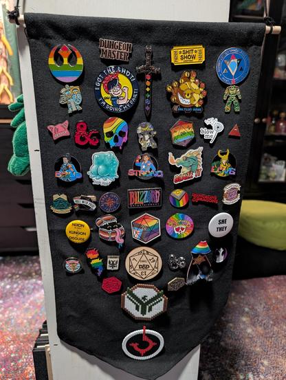 Photo of a hanging banner full of nerdy, queer, and political pins.