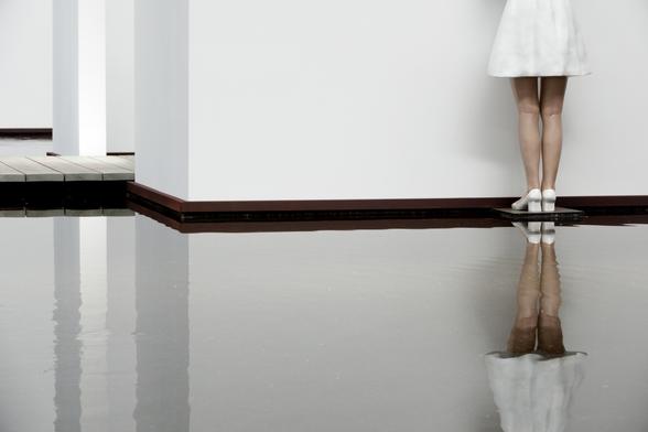 legs of a statue in a museum, reflected in water