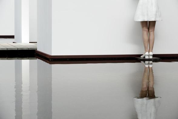 legs of a statue in a museum, reflected in water