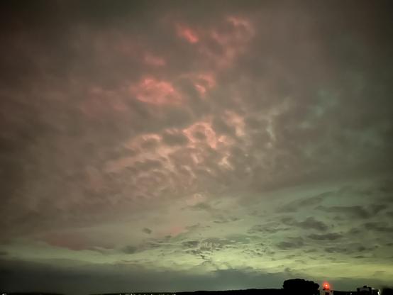 aurora behind some clouds, lots of green on the horizon