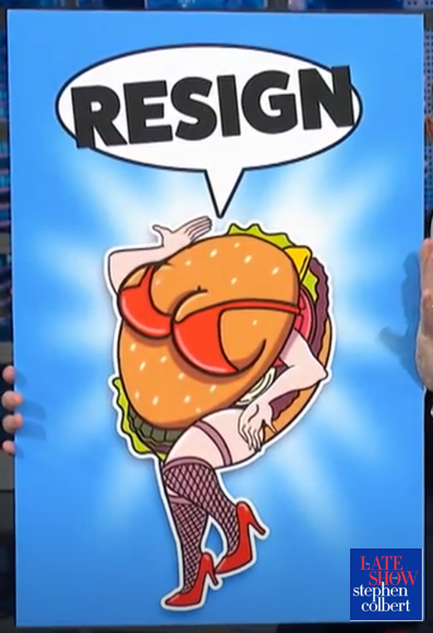 Image from The Late Show with Stephen Colbert. He is holding a posterboard with a picture of a hamburger with leg, stockings, red high heel shoes, big tits in a red bikini, no head, and it says "RESIGN"