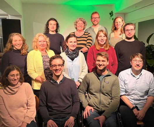 Gruppenfoto in einem Büro. Der Hintergrund ist grün beleuchtet.