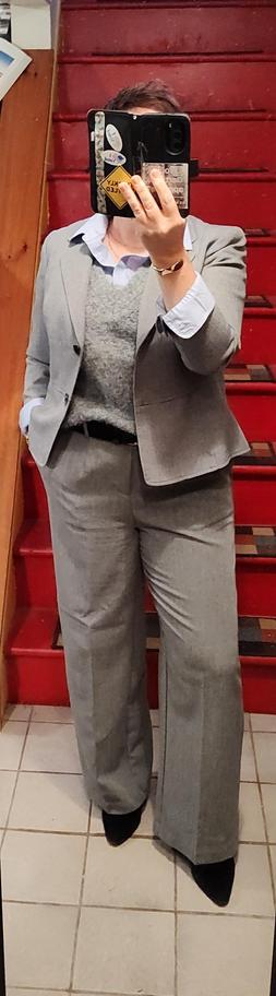 Crisp pale blue button up under grey mohair sweater vest. Pale grey wide-leg trousers, almost matching grey blazer. Black belt and ankle boots. Minimal gold jewelry.