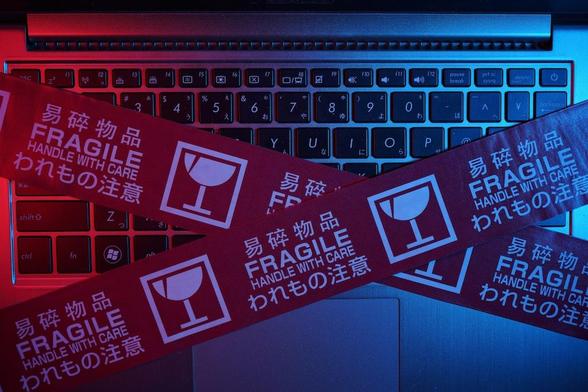 Blick von oben auf einen Laptop, der mit einem Paketband für zerbrechliche Waren versehen ist.