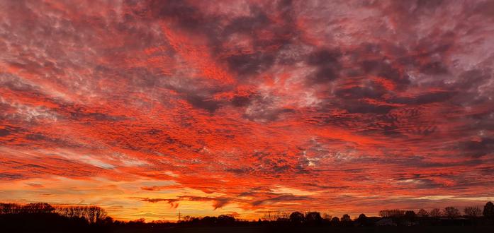 Das Foto zeigt den glutroten Abendhimmel mit rot-orange gefärbten Wolken über Wildes im Landkreis Oldenburg in Niedersachsen.