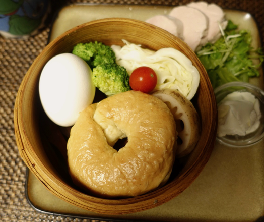 マグカップに注がれたコーヒー、蒸籠で蒸された卵、ブロッコリー、キャベツ、蓮根、ミニトマト、ベーグル。四角皿に盛られた茹で豚ヒレ肉、フリルレタス、クリームチーズが写っている。