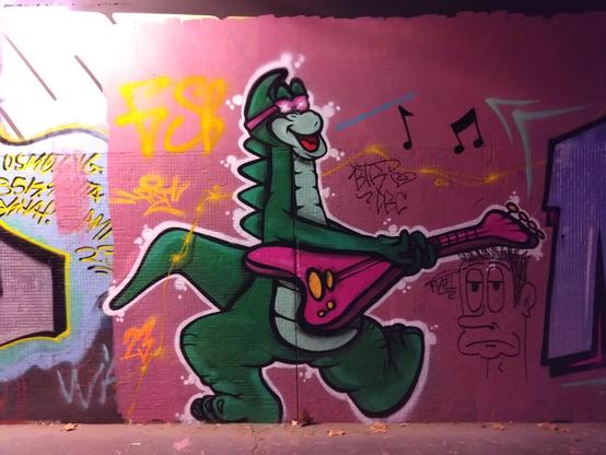 A mural of Denver the Last Dinosaur playing guitar with pink sunglasses.