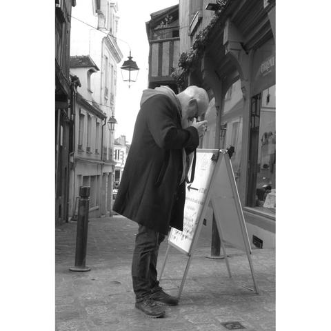 Black and white picture of a man photographing a sewage plate .