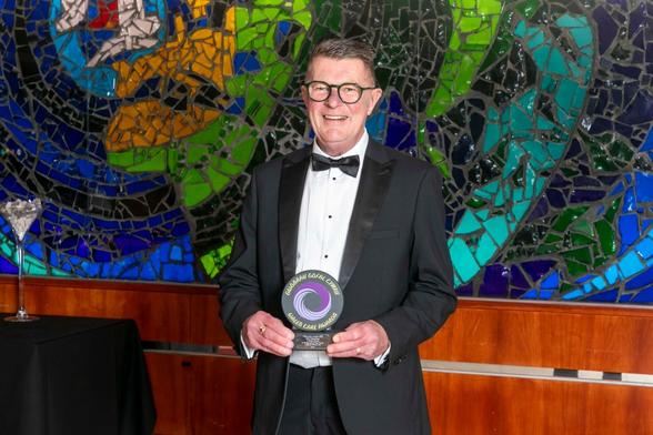 Leslie Whelan, a grandfather from Swansea, smiling as he holds his Gold award at the Wales Care Awards 2025.