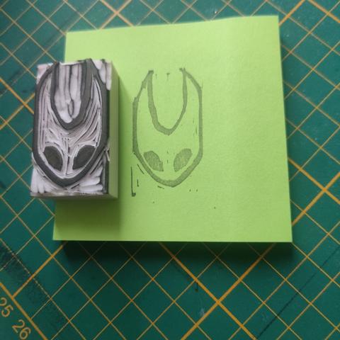 A stamp of Hornet (Hollow Knight and Silksong)'s head on a post-it, and the eraser stamp displayed next to it.