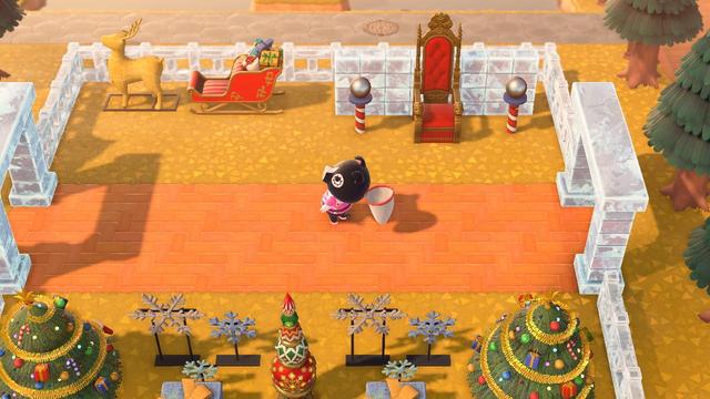 Animal Crossing: New Horizons screenshot. Agnes (black pig with white around her eyes) is wearing a pink zap suit and seen from above walking along a brick path. On the south side of her is assorted symmetrical Christmas decorations including a large tree, light up snowflakes. To the north is a sleigh and light up reindeer (left) and a throne with two "South Poles" on either side of it (right). This entire area is enclosed in ice fencing with an ice archway on either side.
