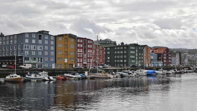 A photo of colorful buildings along a canal. The sky is filled with clouds.