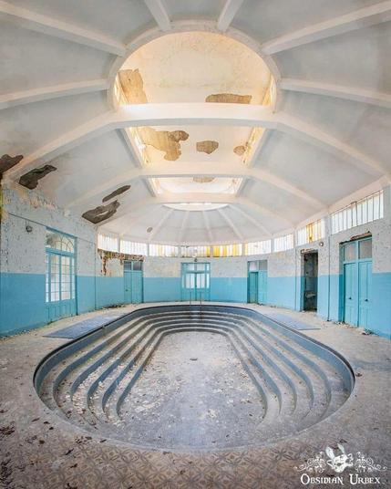 blue room with shallow oval pool. above is an oval skylight