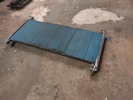 DIY garage creeper ready for use on the floor, with a well worn exercise mat as the padding.