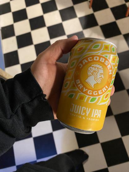Ugens øl - den orange Juicy IPA fra Jacobsen - holdes op over et skakternet gulv