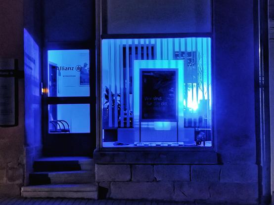 Schaufenster und Glastür in blauer Beleuchtung in der Nacht.