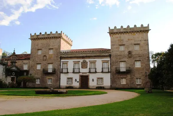The image depicts a large, historic building that appears to be a castle or manor house. It features distinct architectural elements such as two tall towers at either side, a central entrance area, and a courtyard. The exterior has a combination of stone and white surfaces, accented by balconies. The surrounding area includes well-maintained green lawns and landscaping, suggesting it is set in a landscaped garden or park. The overall style conveys a sense of historical significance, typical of structures found in Europe.

Image Credits: Wikimedia / HombreDHojalata / CC BY-SA 3.0