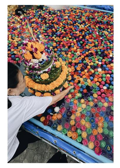 Fotografía de una persona moviendo una ofrenda flotante de flores y velas en el templo Wat Saket Ratchawora Mahawihan.