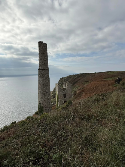 A ruined pump house and stack, nestle in cliffs on the south Cornish coast. They mark the location of an old tin mine. The sea is calm and the air still. And is the home to the elusive Chough - Symbol of Cornwall