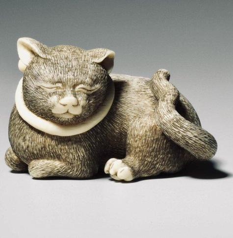 Netsuke. Seated cat, wearing collar, with its eyes closed. Made of ivory.
