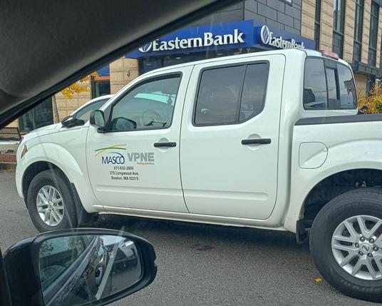 Photo taken looking out the passenger side window, of white pickup truck.  Company name on the driver's door, including "parking solutions"