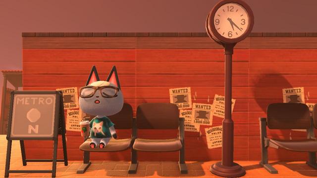 Animal Crossing: New Horizons screenshot. Image of Raymond wearing a green meme cat t-shirt casually sitting on a brown lecture-hall bench in front of a brick wall (back side of a red storefront) with a cup of coffee in his hand. Next to him on the left is a sign that reads "Metro N" and to his right is a bronze park clock followed by another brown lecture-hall bench.